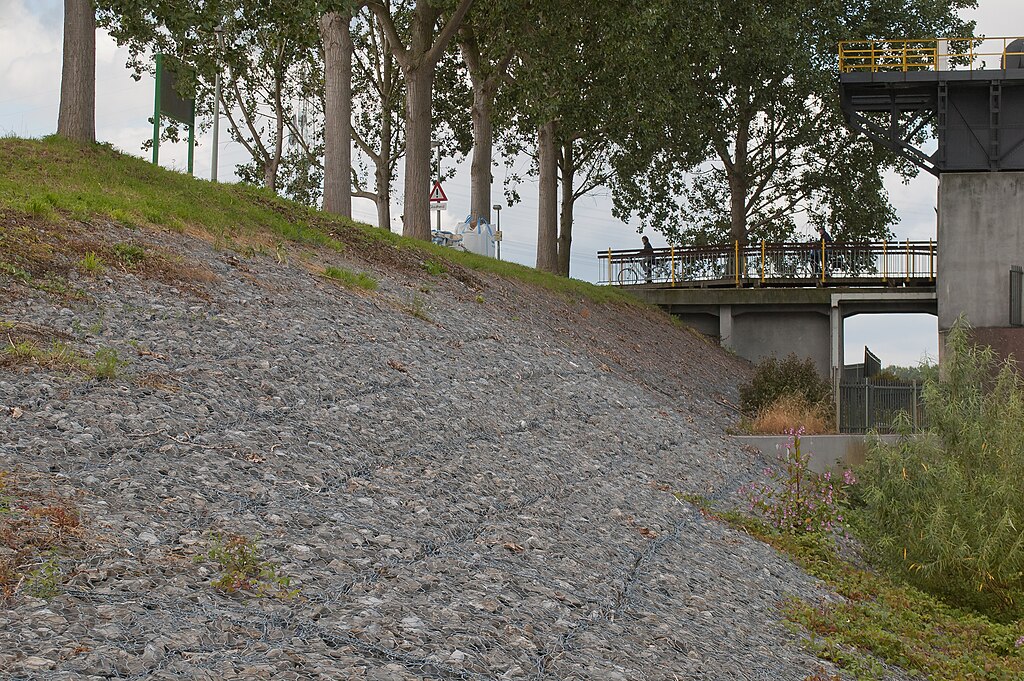 Gabionen als Uferbefestigung eines künstlich in einem Fluss angelegten Dammes (am Stauwehr in der Maas bei Linne, Niederlande)